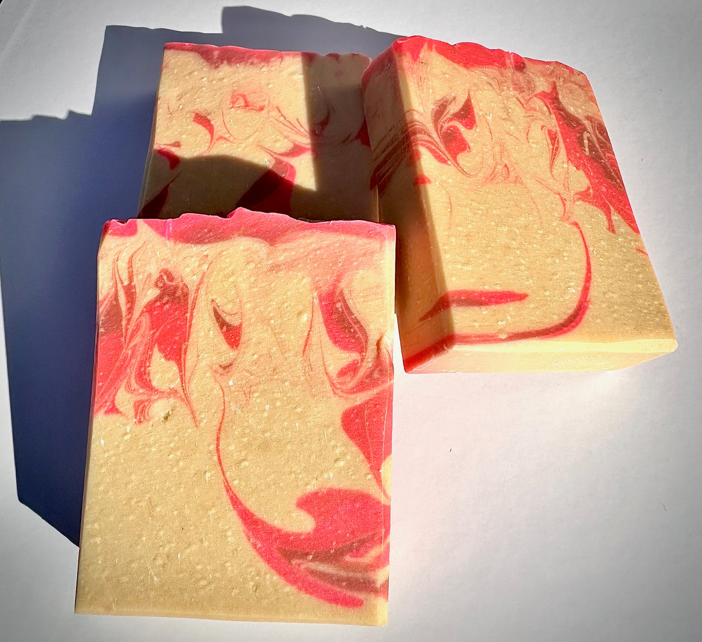 Three bars of soap with a marbled design in red and yellow on a white background