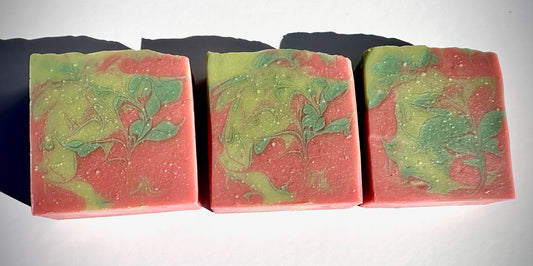 Three bars of soap with green and pink marbled design on a black and white background