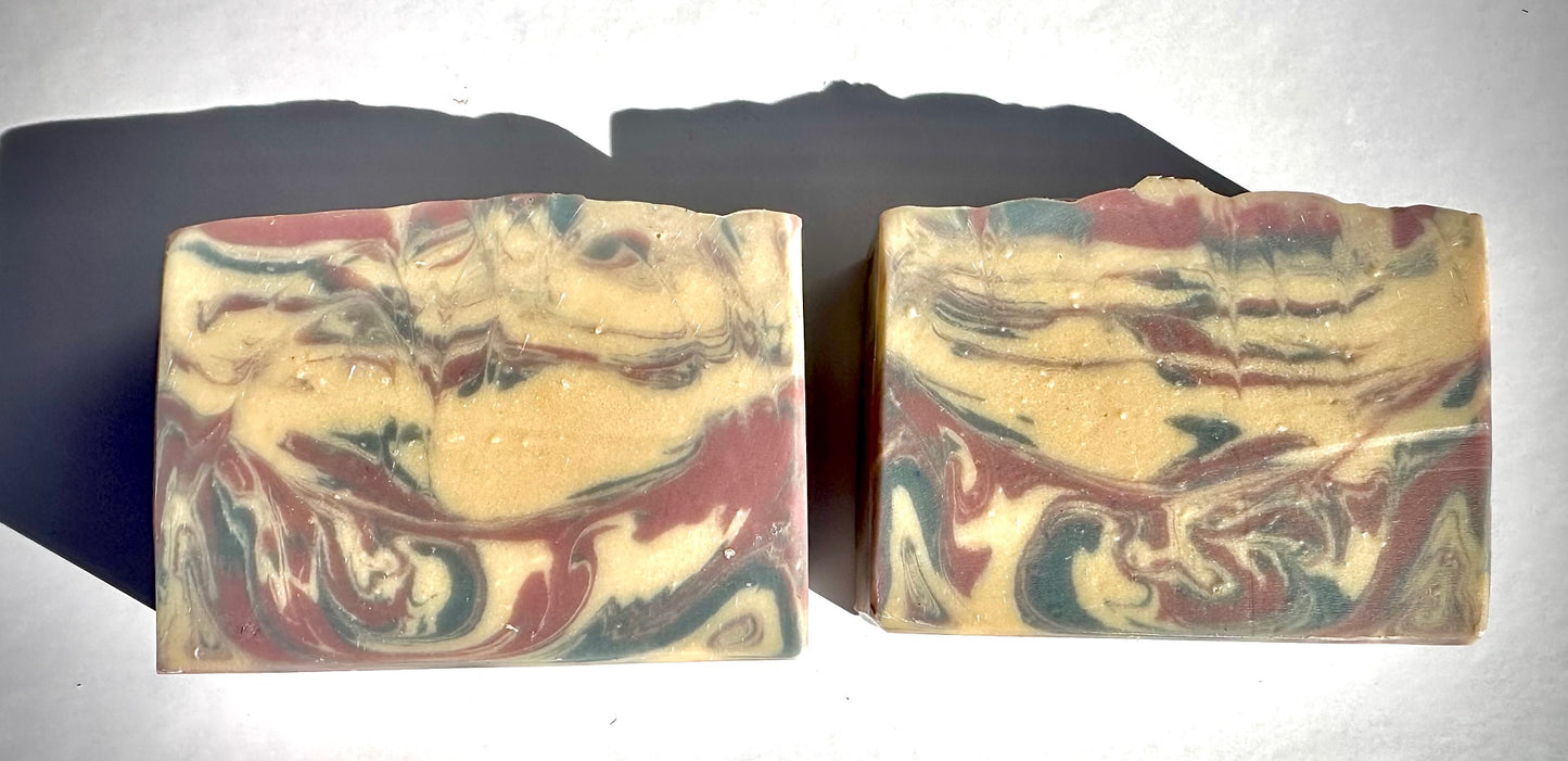 Two marbled soap bars on a reflective surface with a dark background
