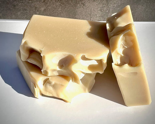 Three bars of soap on a white surface with a neutral background