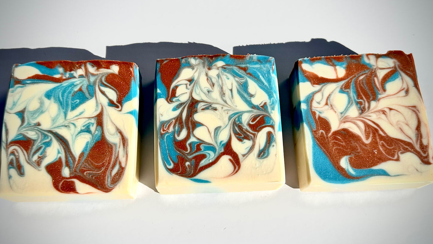 Three bars of soap with marbled design in brown, blue, and white on a white background